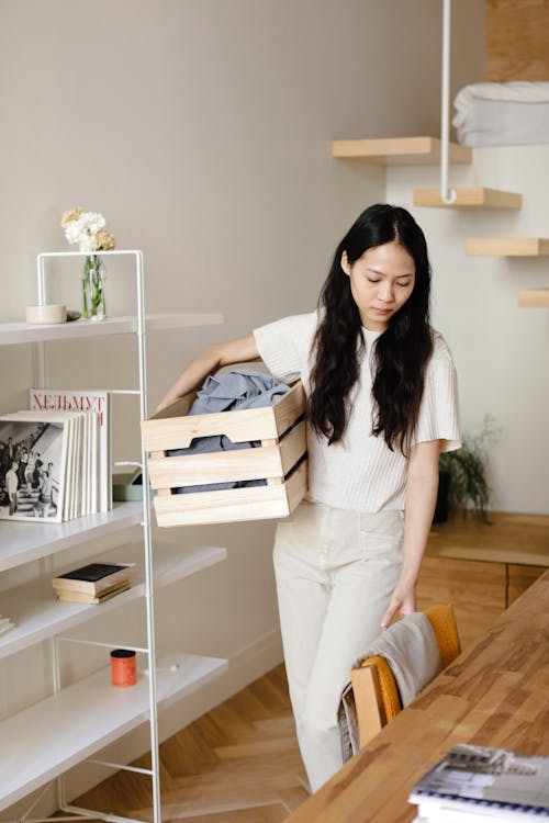 Free Asian woman organizing laundry in a modern home interior, emphasizing cleanliness and minimalism. Stock Photo