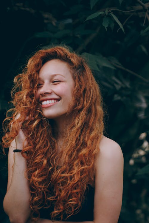 Free A candid portrait of a joyful woman with curly red hair, expressing natural beauty and happiness. Stock Photo