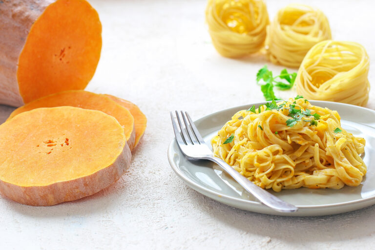 Pumpkin alfredo fettucine pasta in a ceramic plate on white back